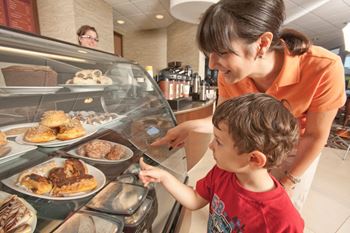 a woman and a child looking at food in a display case